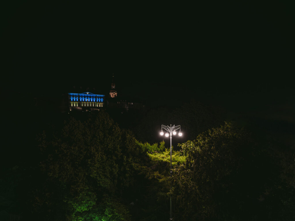 Historical outdoor space lighting design in a park in front of Estonian Parlament building that is lit with Ukranian flag colours on a spring night.