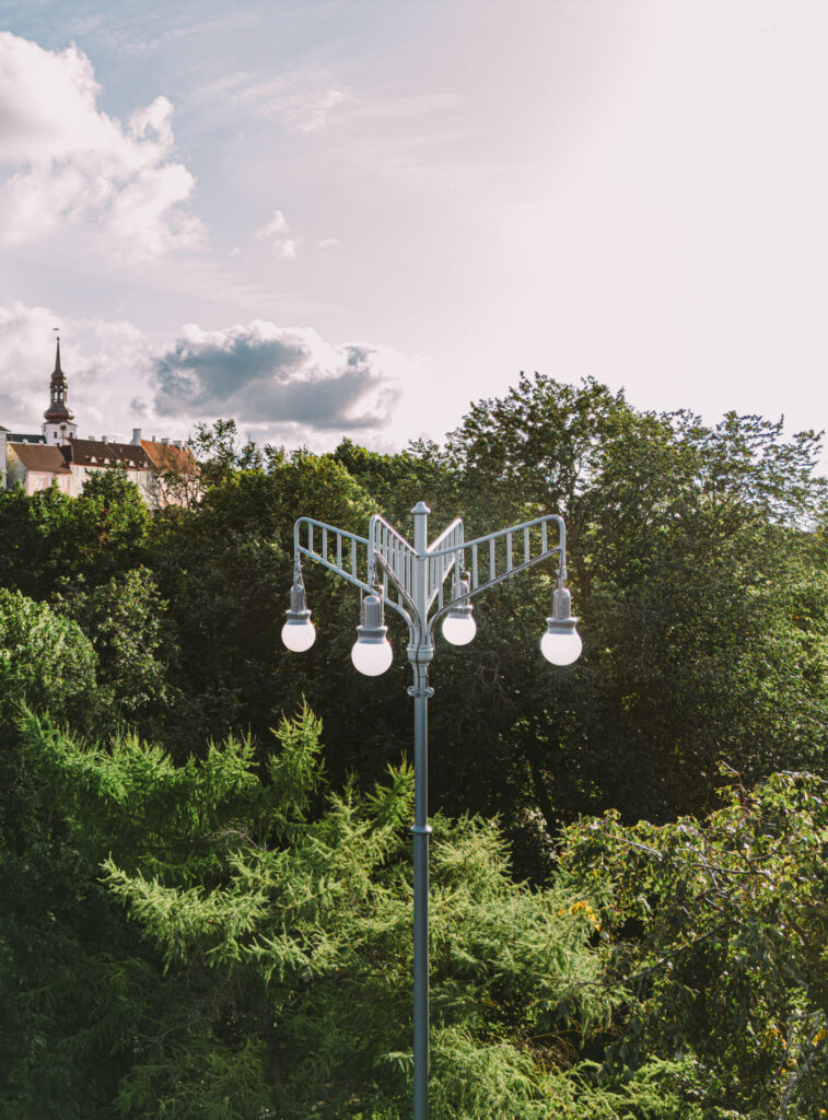 Daytime view of a custom madee historical outdoor light in a park in front of the Estonian Parlament building.