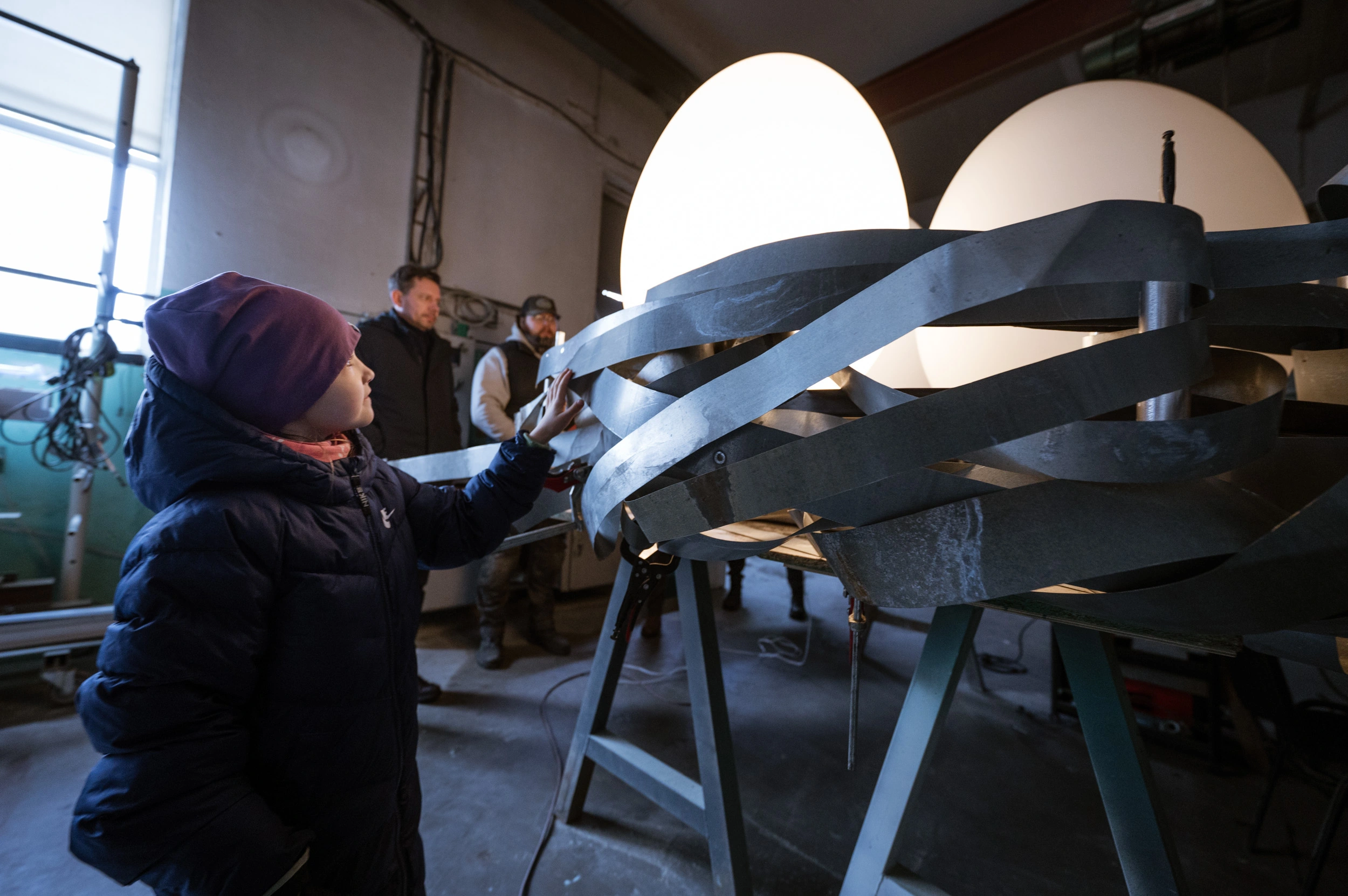 A child engaging with the illuminated NEST public art installation indoors, highlighting its interactive design and glowing light effects.