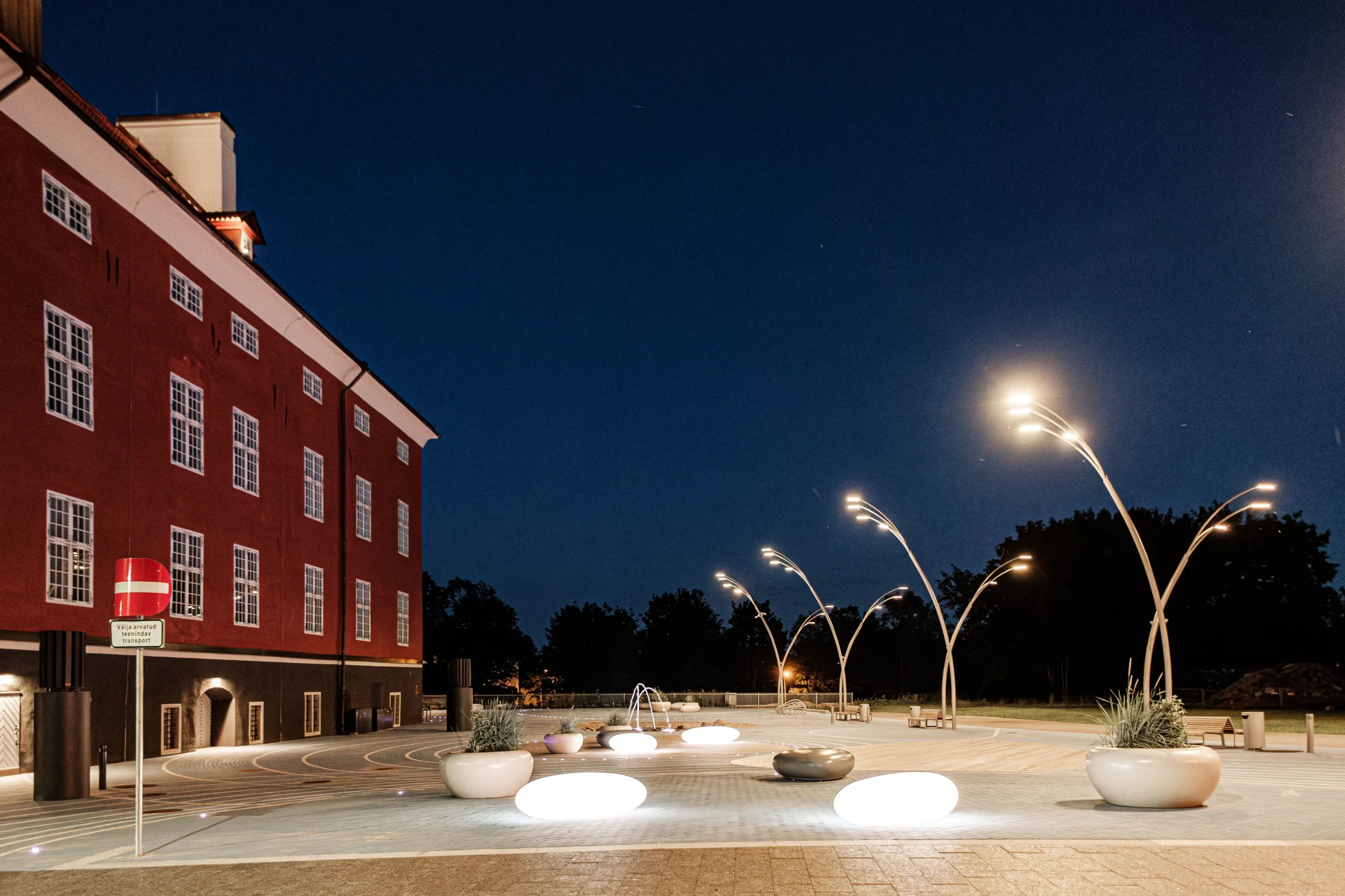 Evening courtyard featuring illuminated seating with pebble-inspired design under reed-inspired lamps.