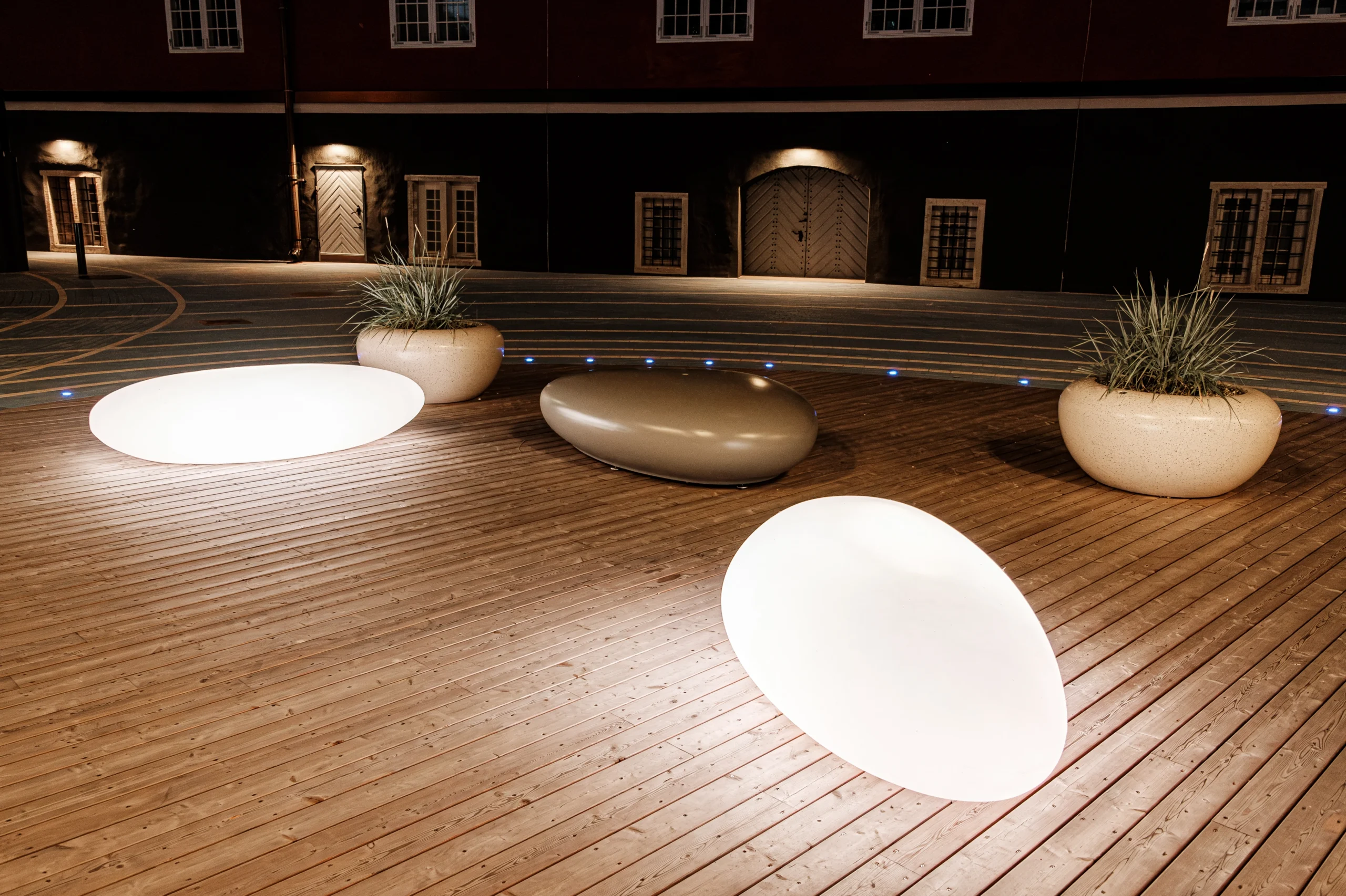 Illuminated urban furniture with glowing pebble-inspired seating in a historic courtyard at night.