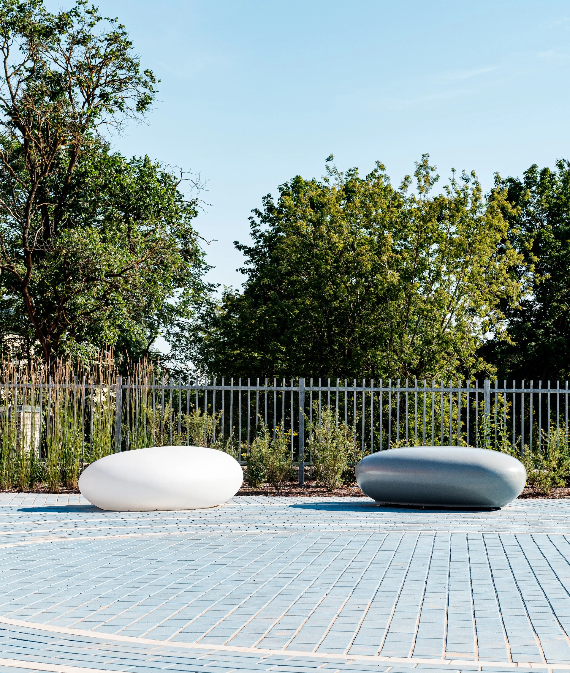 Outdoor park with white pebble-shaped urban seating on geometric blue tiles