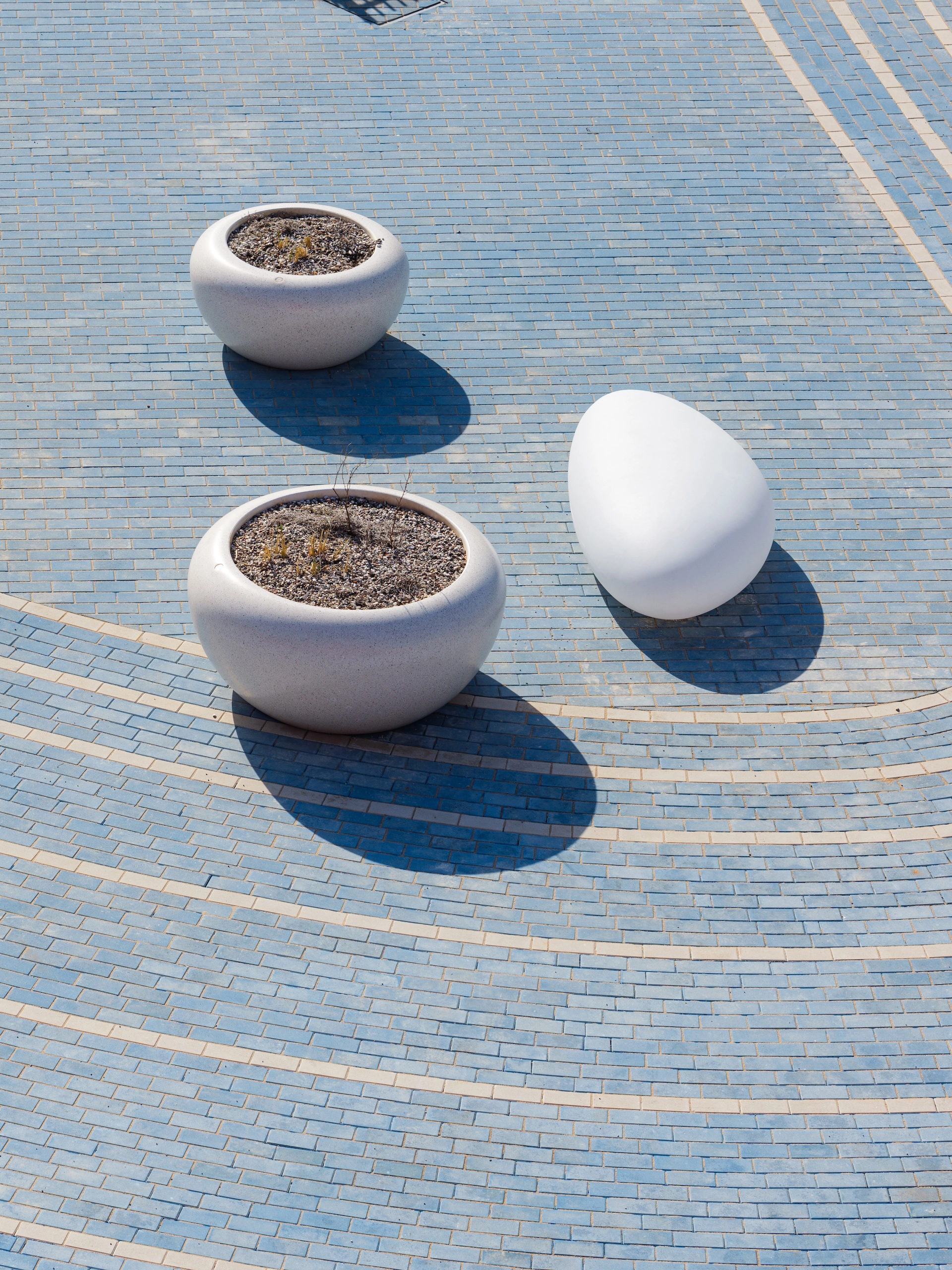 Top-down view of illuminated seating with white pebble-inspired design on blue brick pattern