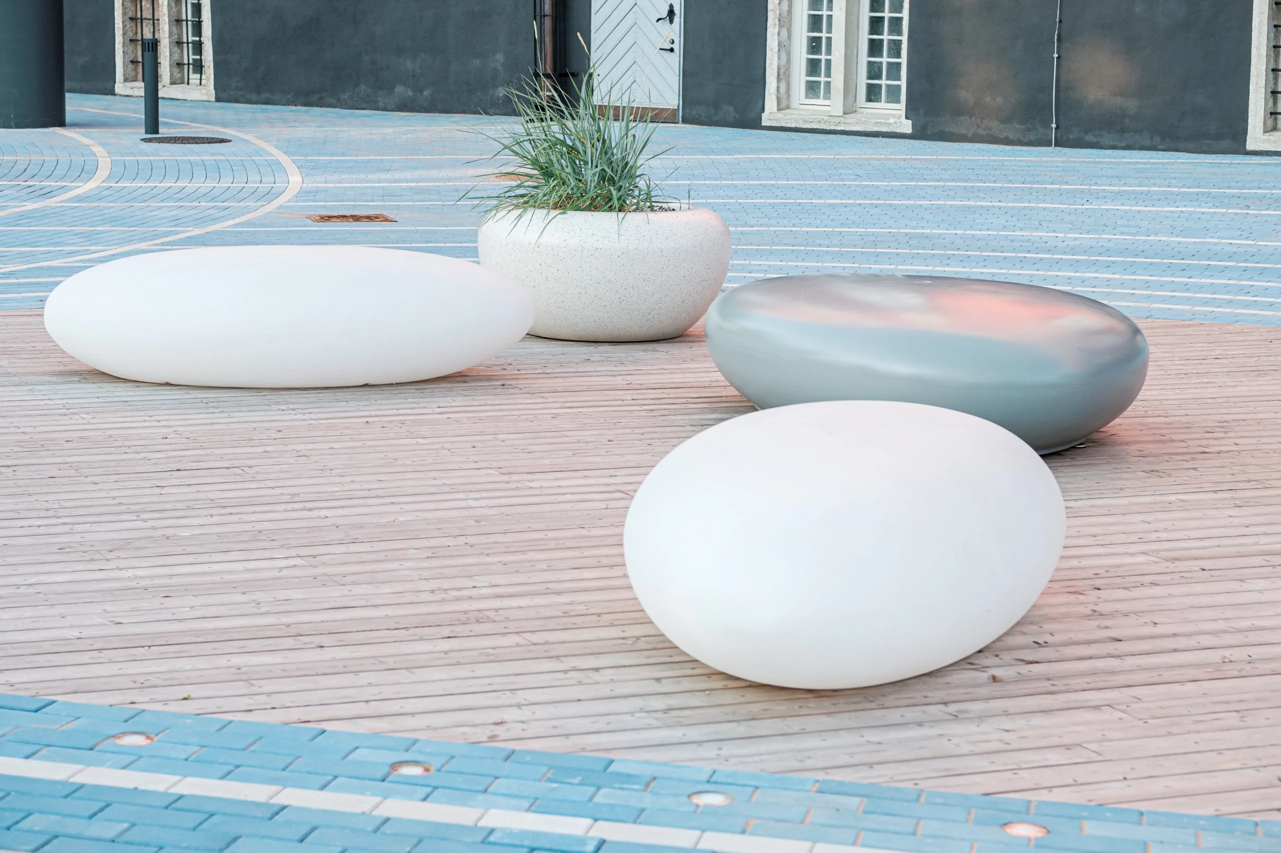 Urban plaza showcasing outdoor furniture with pebble-inspired seating on a wooden deck.