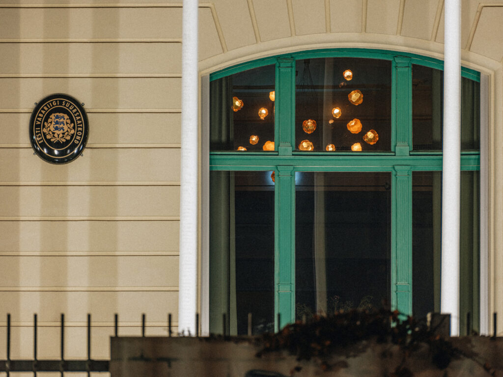 Estonian Embassy facade with crest and Cloudberry lights glowing in the window at night, Berlin