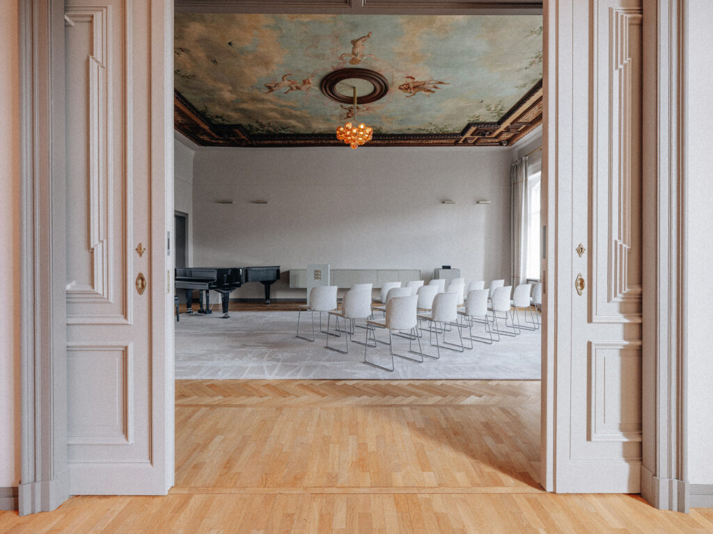 Cloudberry resin light in the embassy hall with a grand piano and seating, Berlin