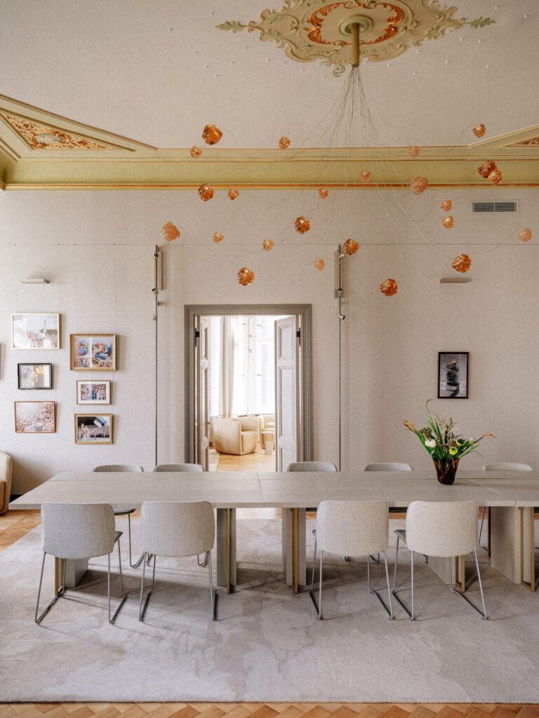 Cloudberry resin lights suspended over a table toward a sunlit doorway, embassy in Berlin