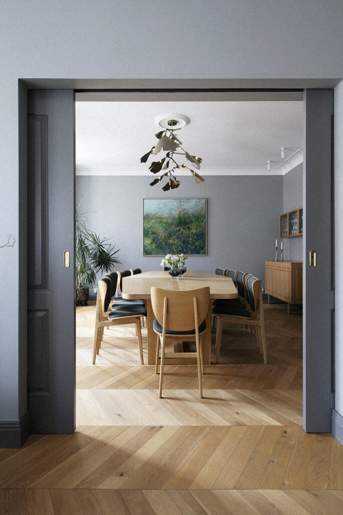 Branching Ginko chandelier over the dining table seen through a doorway, Stockholm