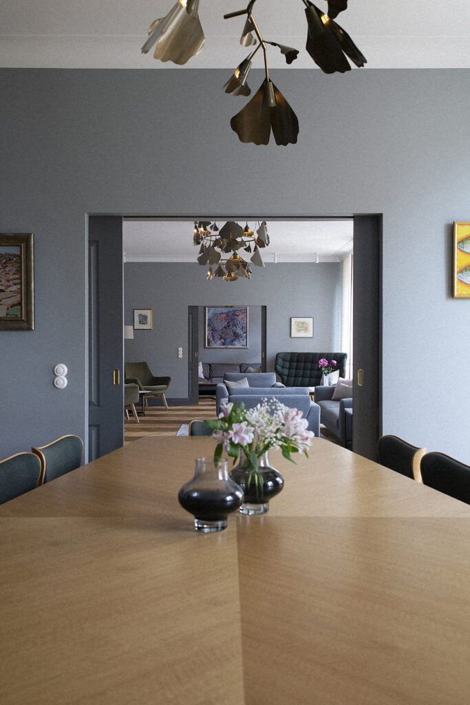 Ginko brass chandeliers over the dining table and living room beyond, Stockholm