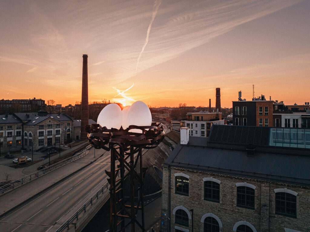 Nest's illuminated eggs on a lattice tower against an orange sunset, Noblessner, Tallinn