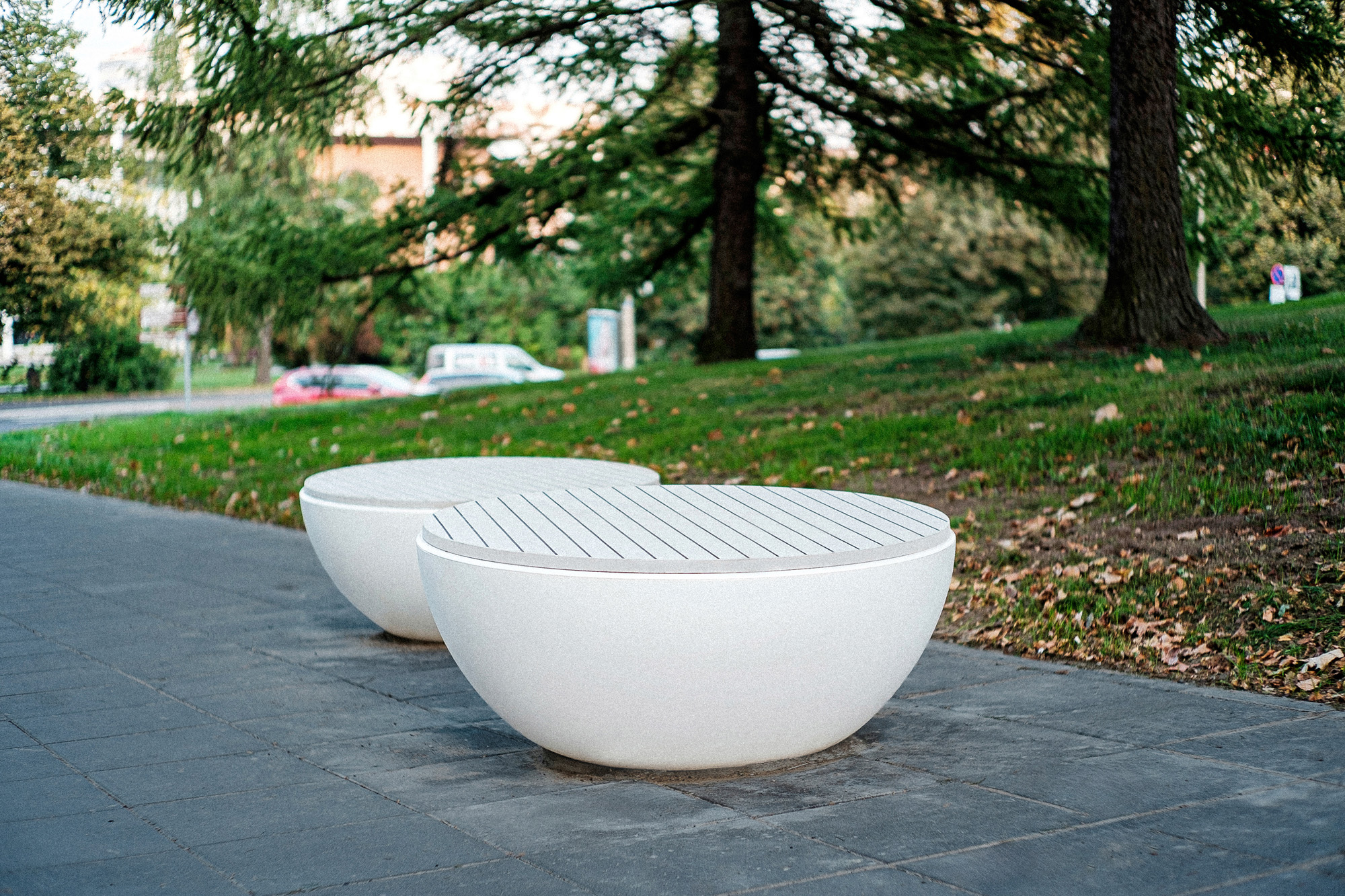 Two Timpan benches under pine trees on Tartu's Vanemuise Street