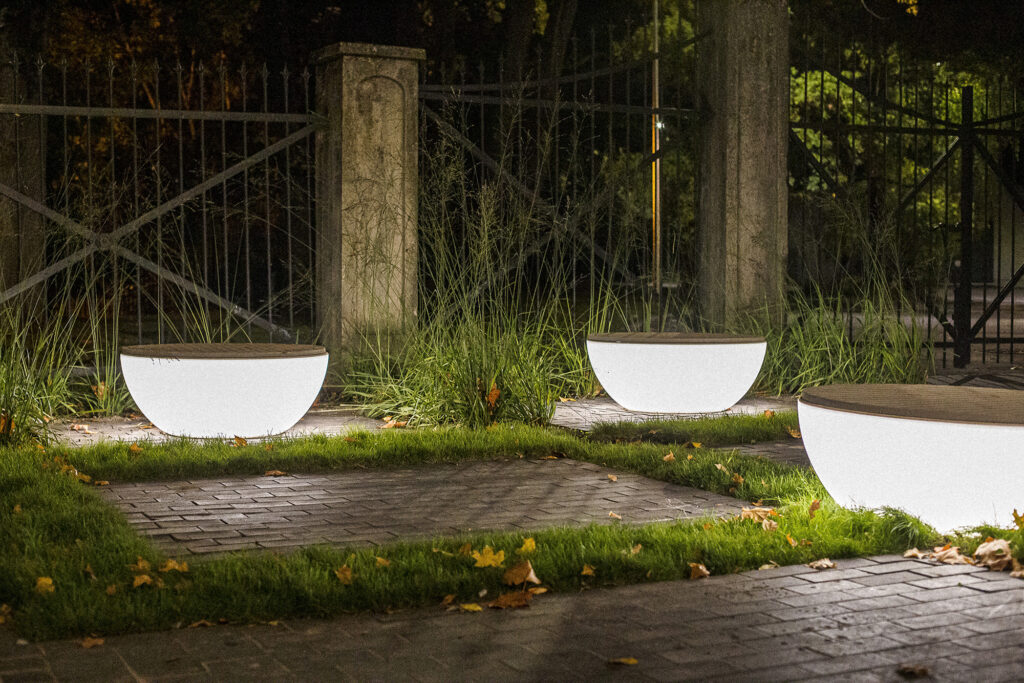 Three Timpan benches glowing beside stone gateposts after dark, Vanemuise Street, Tartu