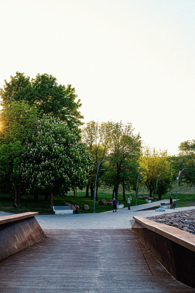 Riverside park at sunset with Tree luminaires and benches along the Narva promenade