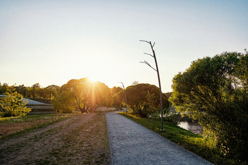Tree promenade lighting along the riverside path at sunset, Narva