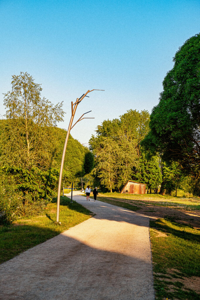 Tree luminaire on the promenade with people walking at golden hour, Narva