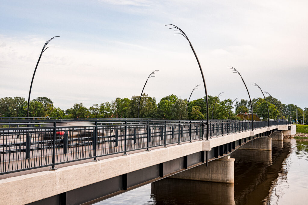 Row of Reed street lights curving along the Salacgriva bridge as a truck crosses at speed.
