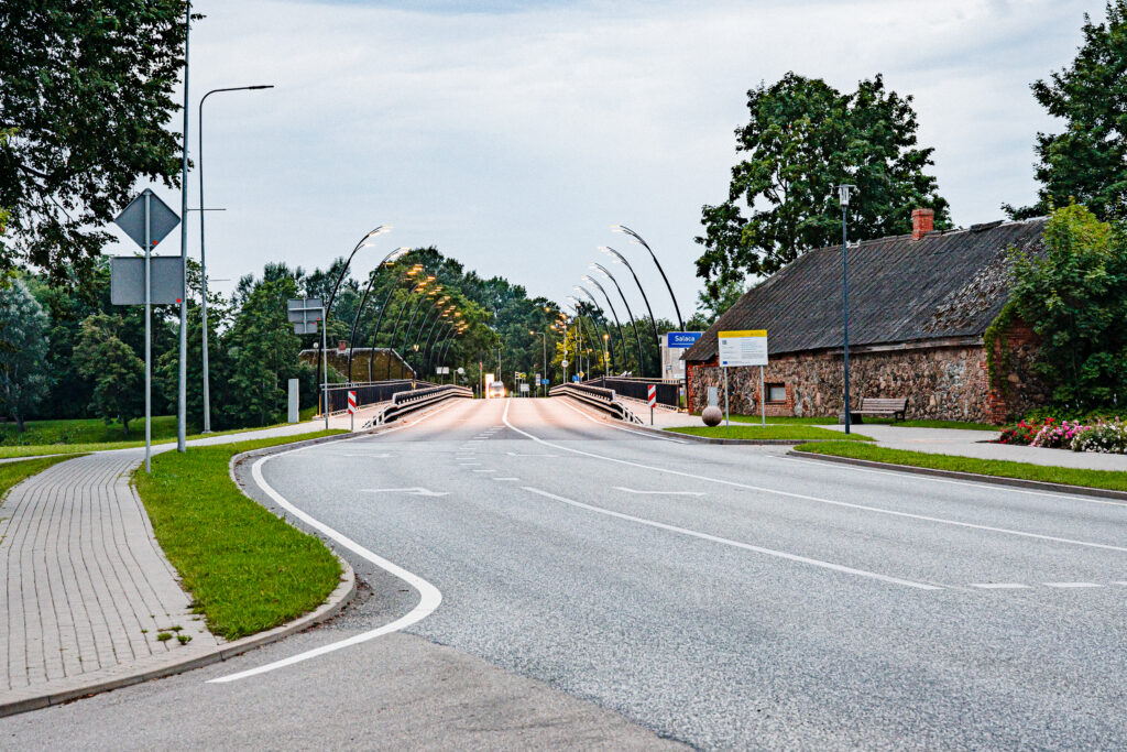 Reed street lighting along the road into Salacgriva, with the old stone building and church spire beyond.